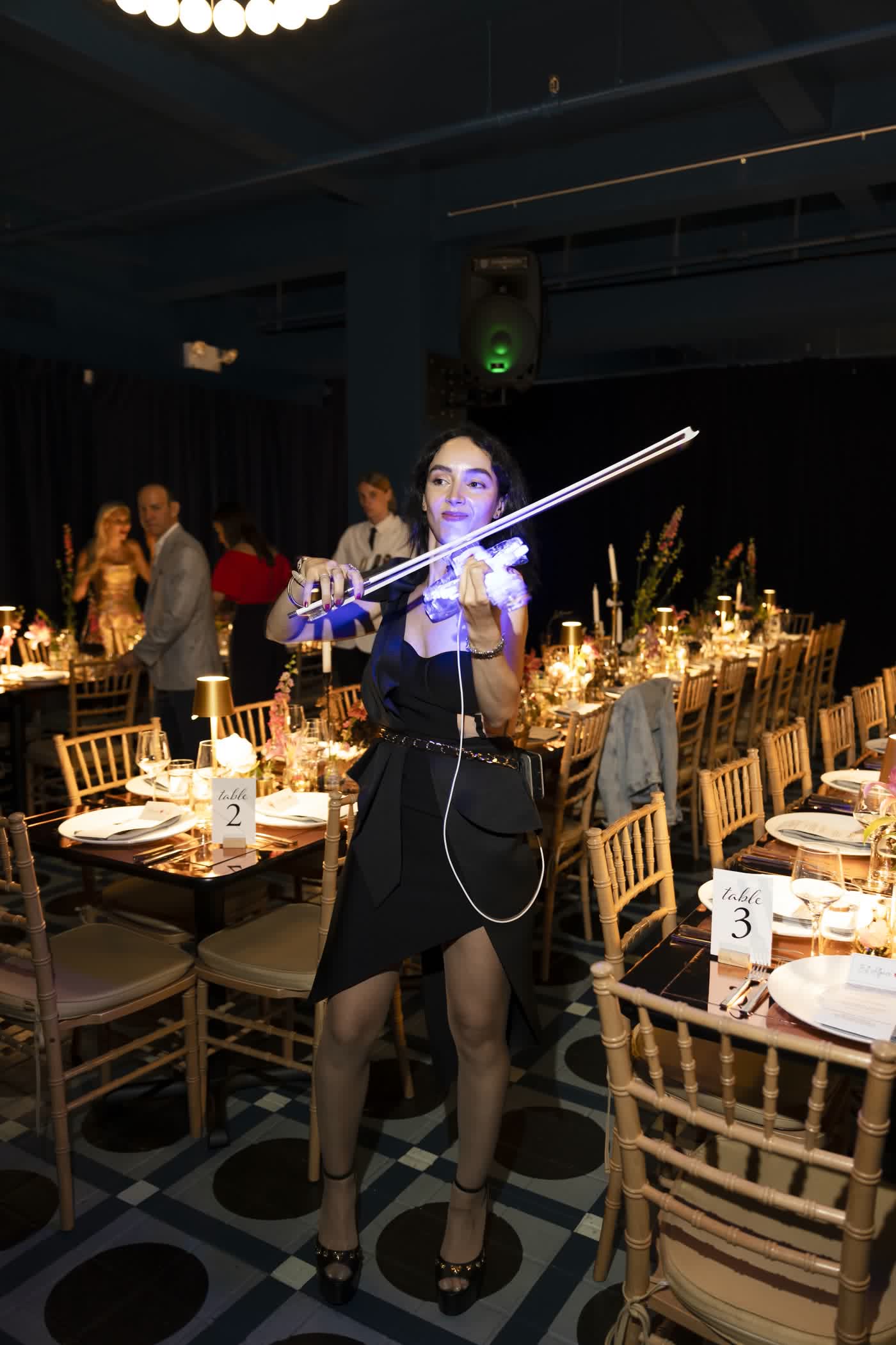 The lit violin along gold-set gala tables