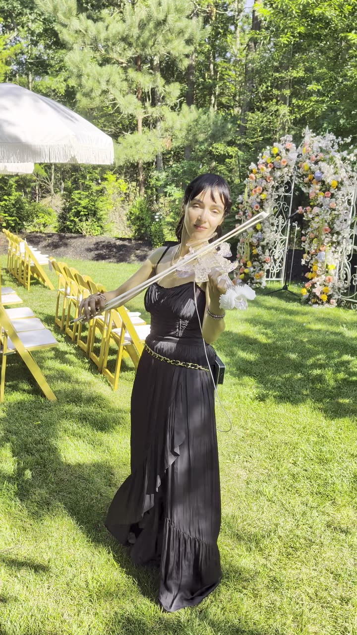 Sadie playing a real garden wedding ceremony, floral arch behind her