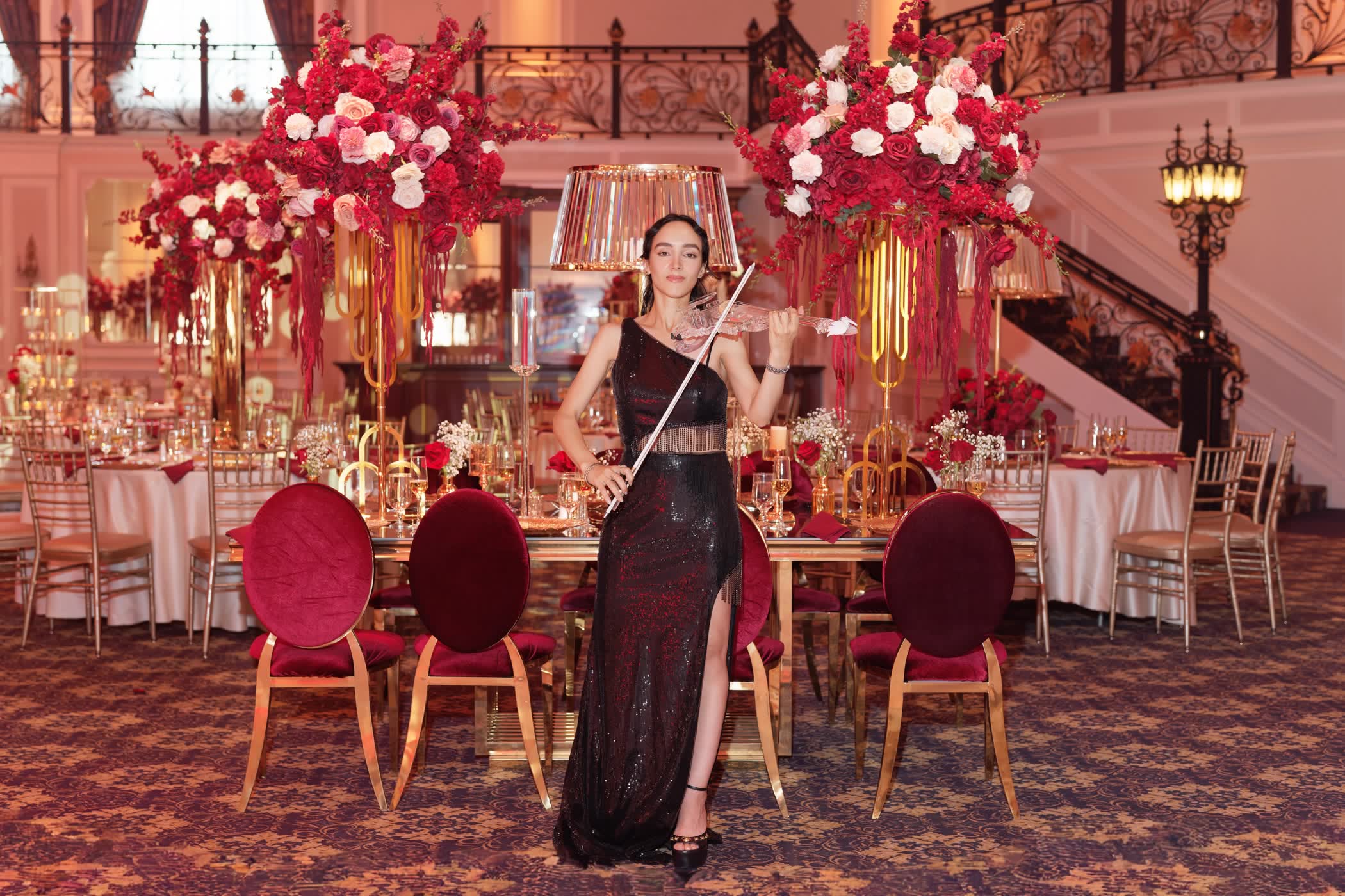 Sadie playing the transparent violin between red-and-gold dinner tables at The Legacy Castle