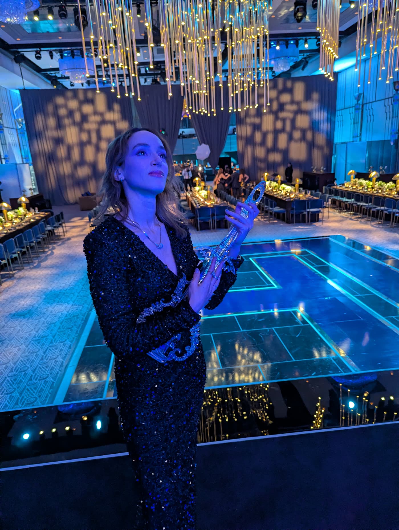 Sadie above a blue-lit sunken court at an evening event