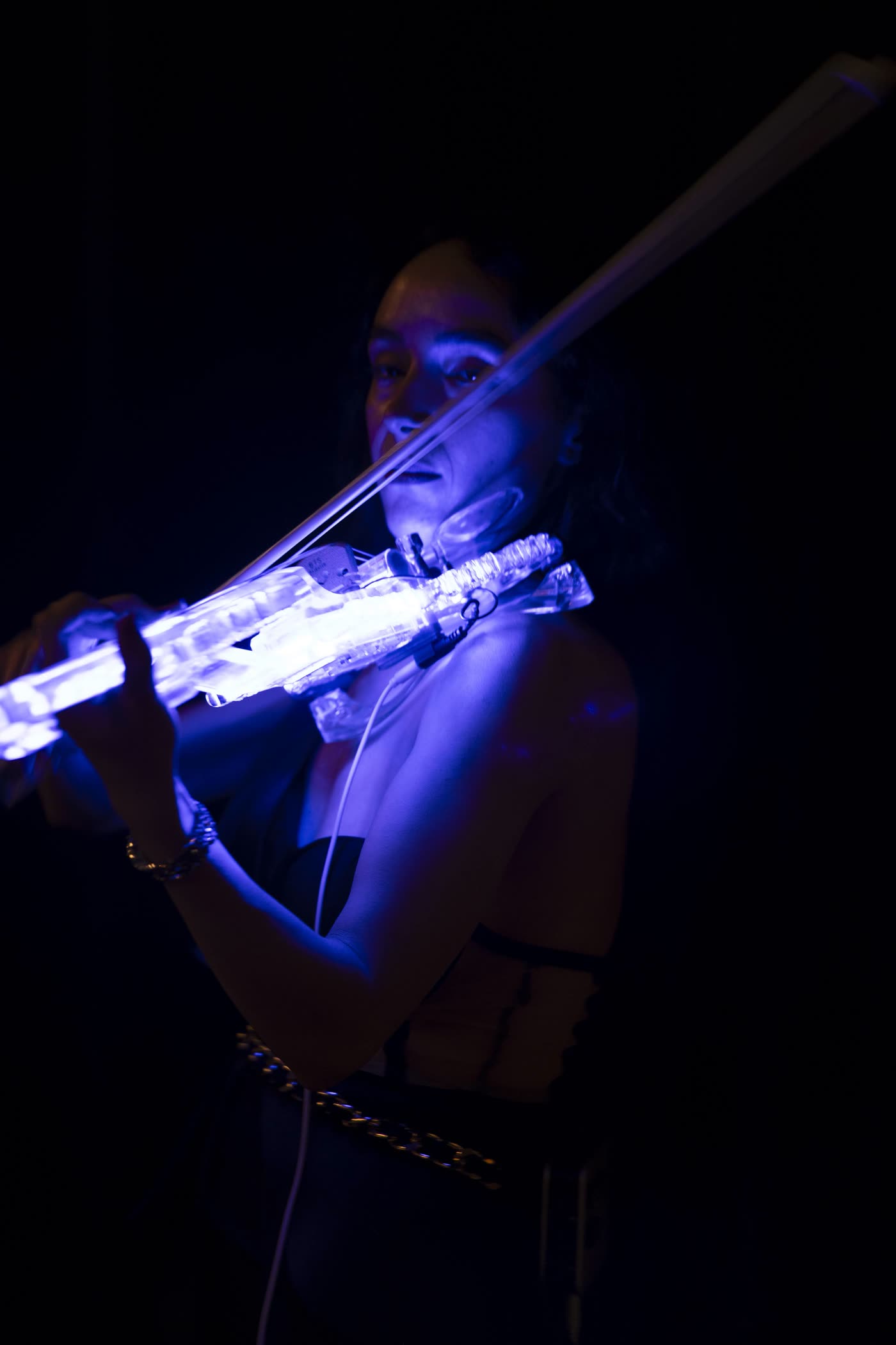 The transparent violin glowing blue, close up in the dark