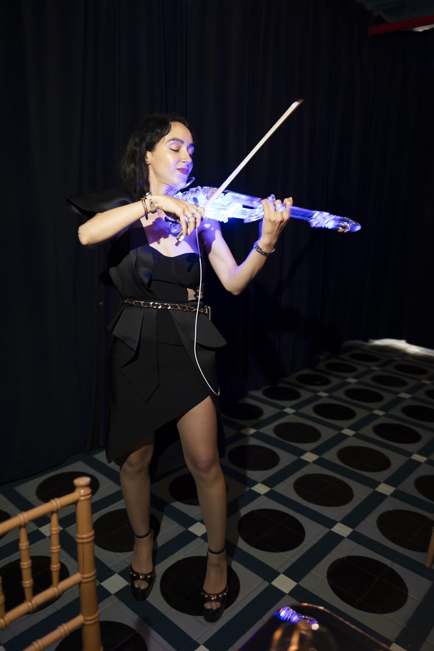 Sadie playing the transparent violin glowing blue against a dark stage